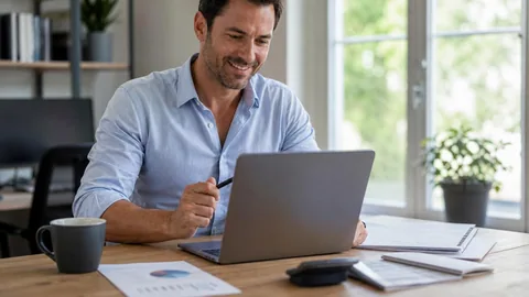 Smiling man reviewing a budget on his laptop at a home-office desk