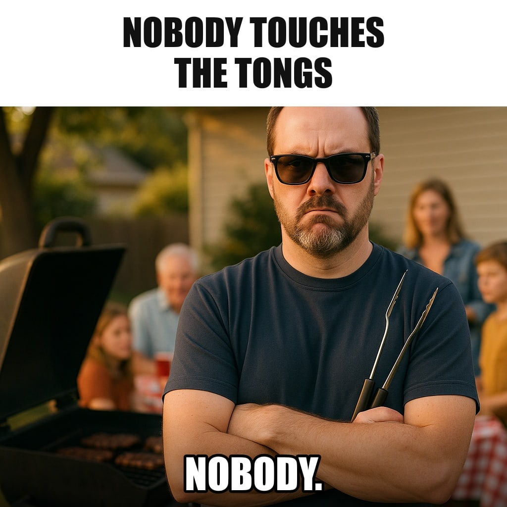 A serious dad in sunglasses standing guard in front of a backyard grill like a bodyguard, arms crossed, holding barbecue tongs, family party blurred behind him. Caption: "Nobody touches the tongs Nobody."